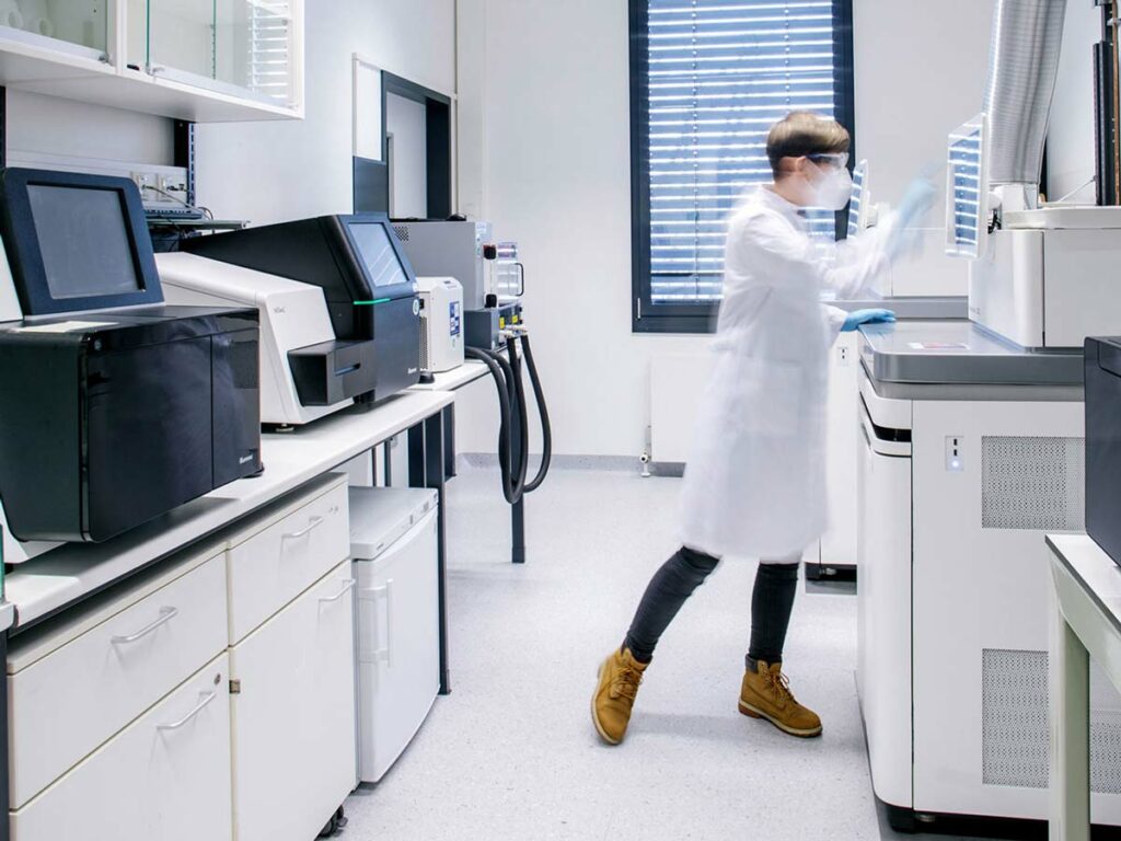 Ein Wissenschaftler steht im Labor des Biotech Unternehmens LAMPseq Diagnostics in Bonn und bedient ein Sequenziergerät von Illumina